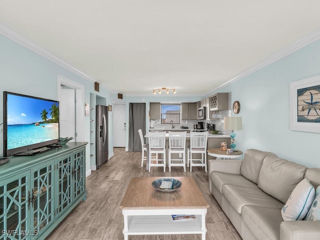 living room featuring light hardwood / wood-style flooring, sink, and crown molding