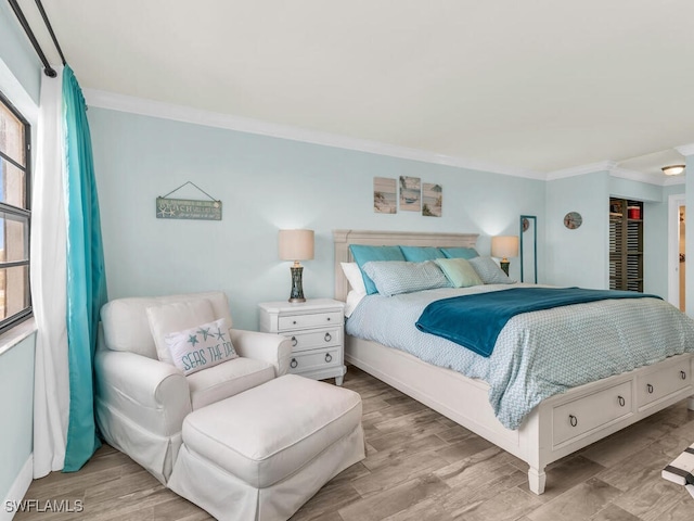 bedroom with baseboards, crown molding, and light wood-type flooring