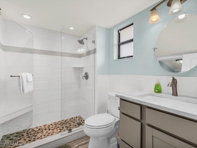 full bathroom featuring a shower stall, toilet, vanity, and tile walls
