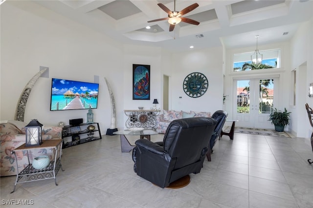 living room with coffered ceiling, french doors, beam ceiling, a towering ceiling, and ceiling fan with notable chandelier