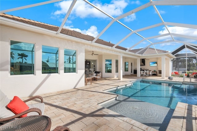 view of swimming pool with a patio area, glass enclosure, and ceiling fan