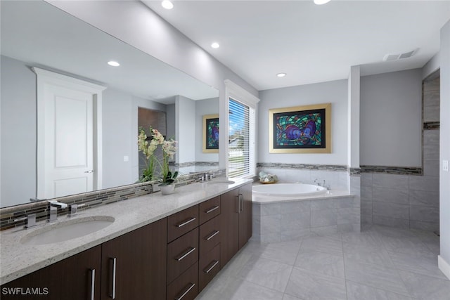 bathroom featuring vanity, tiled tub, and tile patterned flooring