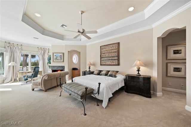 carpeted bedroom featuring ceiling fan, crown molding, and a tray ceiling