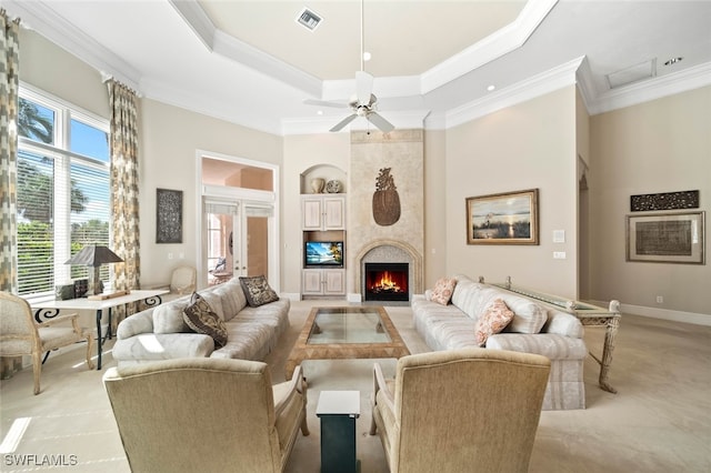 living room featuring a premium fireplace, crown molding, a tray ceiling, and ceiling fan