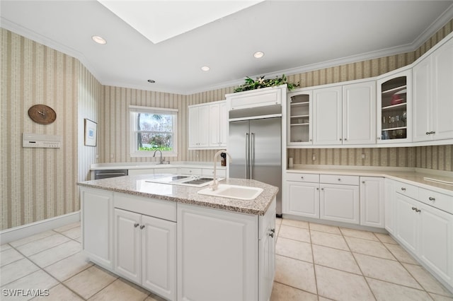 kitchen with built in refrigerator, a kitchen island with sink, light tile patterned flooring, and ornamental molding