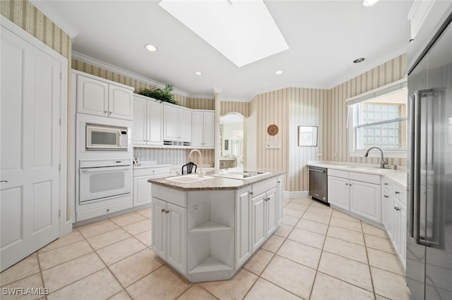 kitchen with white cabinets, a kitchen island with sink, white appliances, and ornamental molding