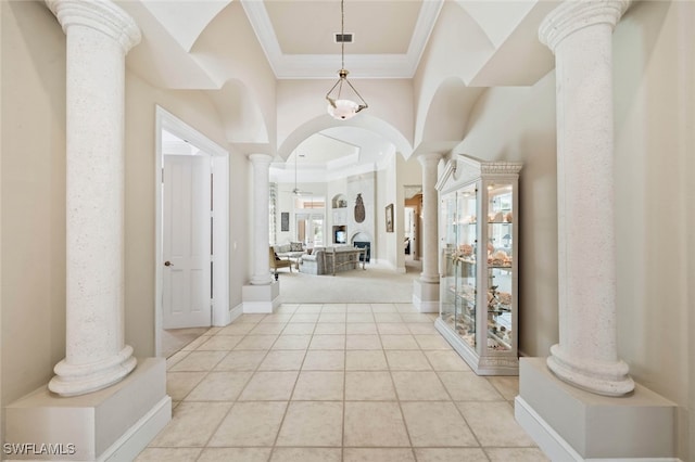 tiled foyer with crown molding and decorative columns