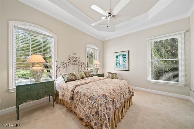 bedroom with ceiling fan, light carpet, a tray ceiling, and multiple windows