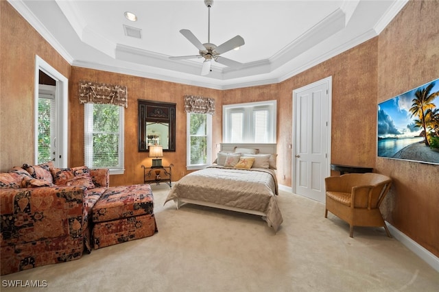 bedroom with ceiling fan, a tray ceiling, and multiple windows