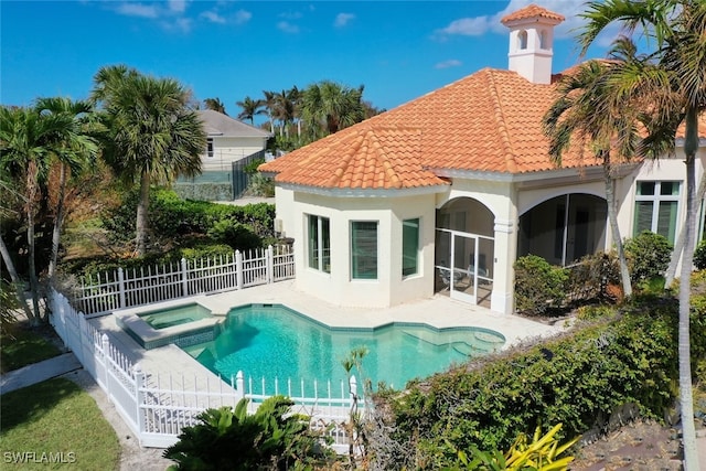 rear view of property featuring a patio area and a swimming pool with hot tub