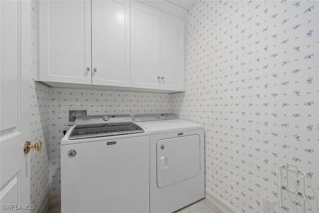 clothes washing area with cabinets and washing machine and clothes dryer