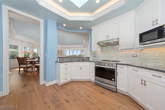 kitchen with light hardwood / wood-style flooring, white cabinets, stainless steel appliances, and ornamental molding