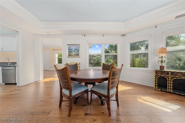 dining space with light hardwood / wood-style floors, ornamental molding, and sink