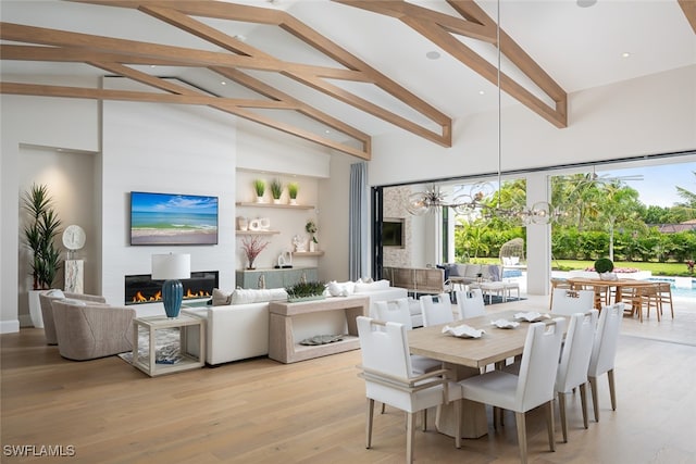 dining area with beam ceiling, high vaulted ceiling, and light hardwood / wood-style floors