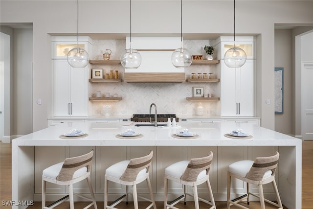 kitchen with a breakfast bar area, a kitchen island with sink, sink, and hanging light fixtures