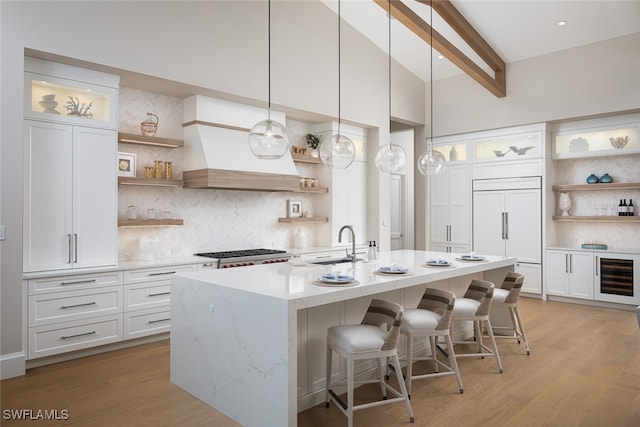 kitchen featuring white cabinetry, hanging light fixtures, paneled refrigerator, and light wood-type flooring