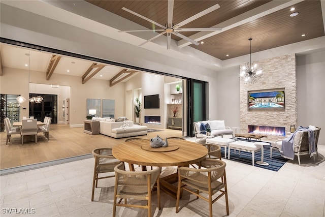 dining area featuring beamed ceiling, a stone fireplace, and wood ceiling