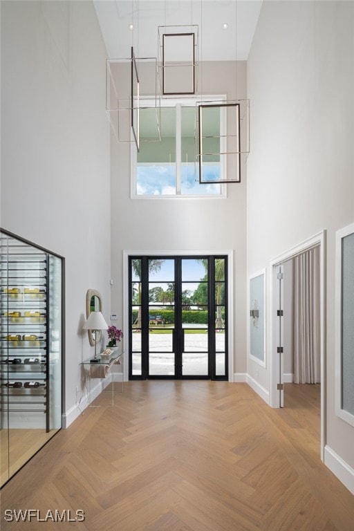 foyer entrance featuring a high ceiling, light parquet flooring, and french doors