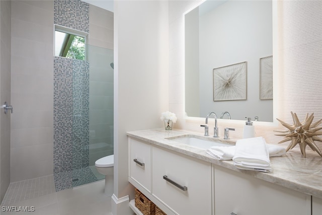 bathroom featuring tiled shower, vanity, toilet, and tile patterned flooring