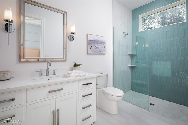 bathroom with toilet, vanity, and tiled shower