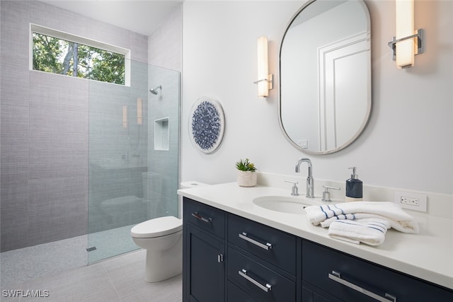 bathroom with a tile shower, vanity, and toilet