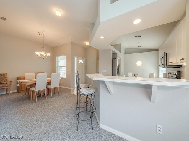 kitchen with a kitchen breakfast bar, white cabinetry, light colored carpet, and appliances with stainless steel finishes