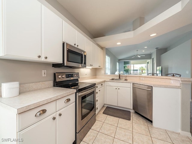 kitchen with lofted ceiling, sink, white cabinetry, and stainless steel appliances