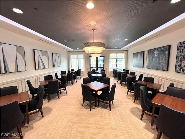 carpeted dining area featuring a raised ceiling and a chandelier