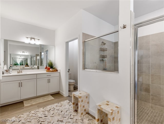 bathroom with hardwood / wood-style flooring, vanity, toilet, and an enclosed shower