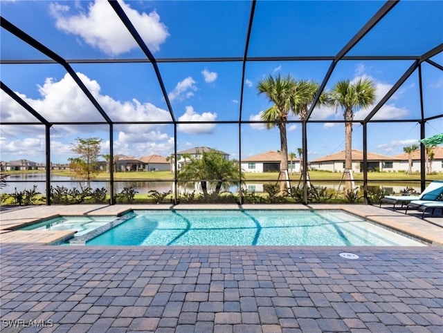 view of pool with glass enclosure, a patio area, a water view, and an in ground hot tub