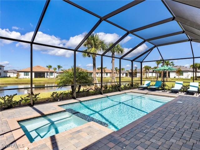 view of pool featuring glass enclosure, a patio area, and a water view