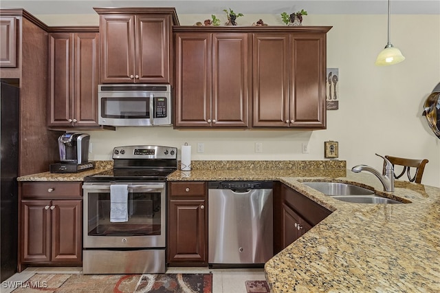 kitchen featuring sink, decorative light fixtures, light stone counters, and stainless steel appliances