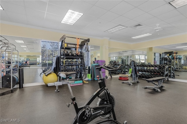 exercise room with a healthy amount of sunlight, ornamental molding, and a drop ceiling