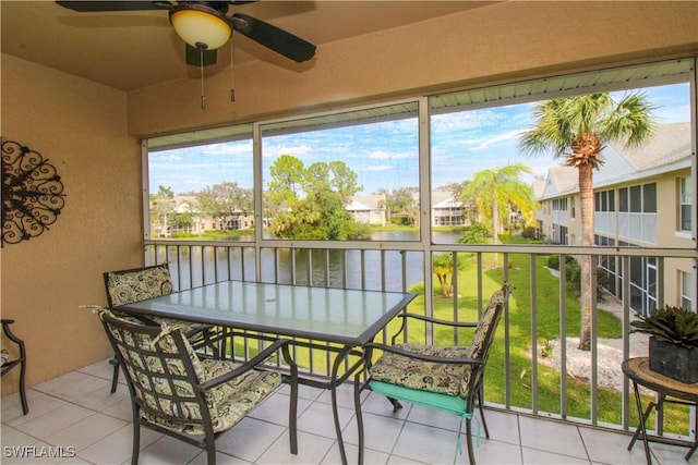 sunroom featuring ceiling fan and a water view