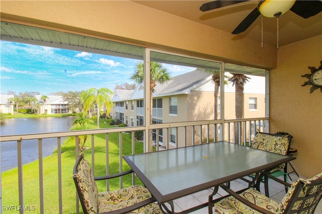 sunroom featuring ceiling fan and a water view