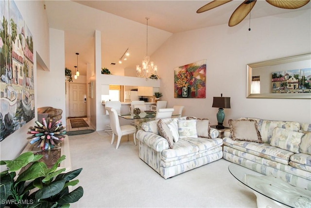 carpeted living room with high vaulted ceiling and ceiling fan with notable chandelier