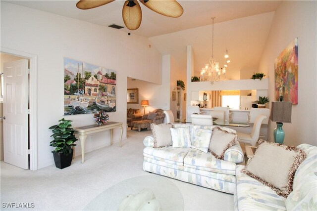 carpeted living room with ceiling fan with notable chandelier and high vaulted ceiling