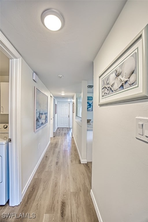 hall with washer / clothes dryer and light wood-type flooring