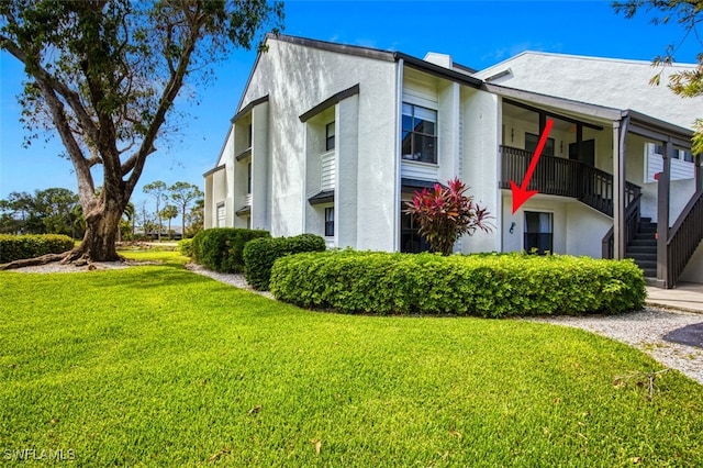 view of side of home featuring a yard and a balcony