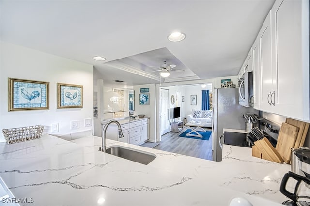 kitchen with light hardwood / wood-style flooring, stainless steel appliances, sink, white cabinets, and light stone counters