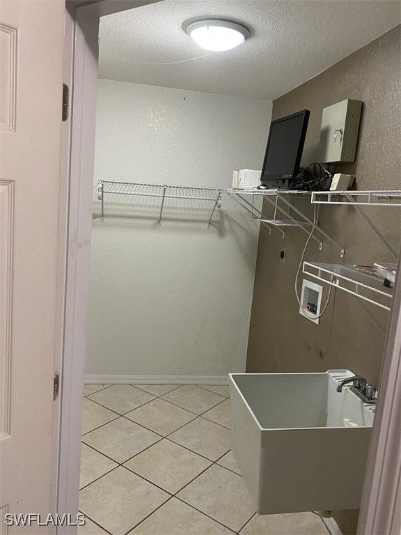 walk in closet featuring sink and light tile patterned floors