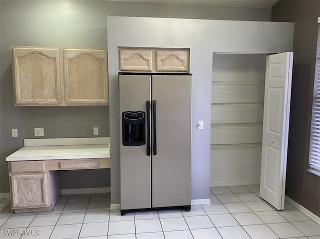 kitchen featuring light tile patterned flooring, light brown cabinets, and fridge with ice dispenser