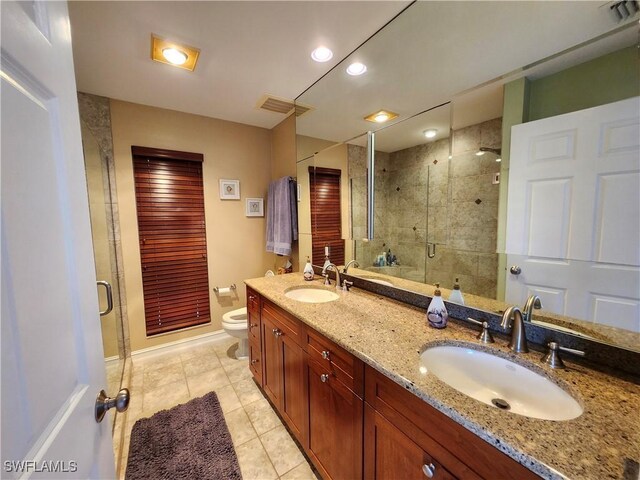 bathroom featuring vanity, toilet, a shower with shower door, and tile patterned flooring