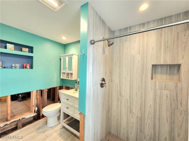 bathroom with vanity, toilet, and tiled shower