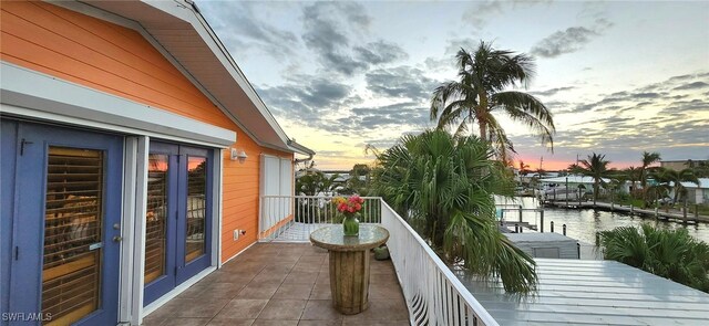 balcony at dusk featuring a water view