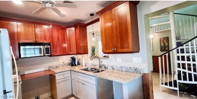 kitchen featuring sink, hanging light fixtures, light tile patterned floors, white refrigerator, and light stone countertops