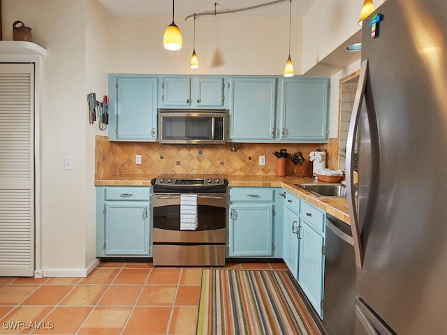 kitchen with blue cabinets, pendant lighting, stainless steel appliances, and tasteful backsplash