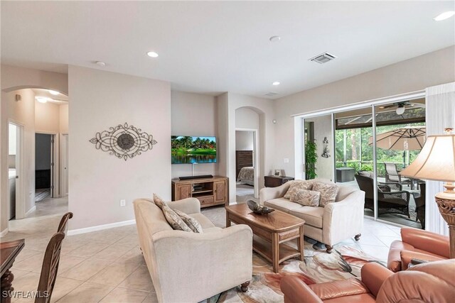 living area featuring arched walkways, recessed lighting, baseboards, light tile patterned floors, and visible vents