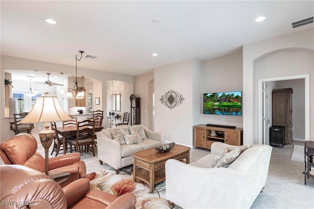 living area featuring light tile patterned floors, arched walkways, recessed lighting, and visible vents