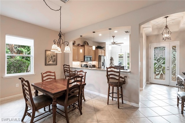 dining space featuring light tile patterned flooring and ceiling fan with notable chandelier